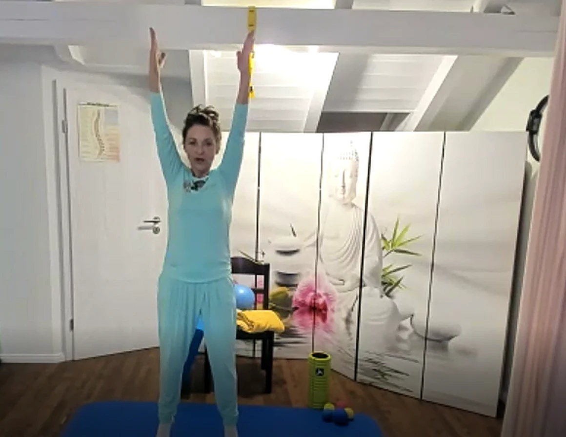 Regina Hafner zeigt eine Dehnübung mit erhobenen Armen im Online-Live-Training